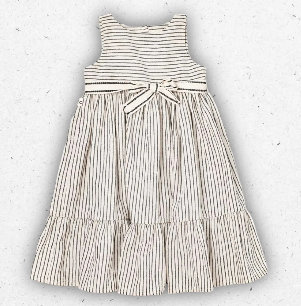 Abito smanicato da bambina Maperò in cotone bianco con sottili righe grigie, cintura con fiocco in vita e balza sul fondo.