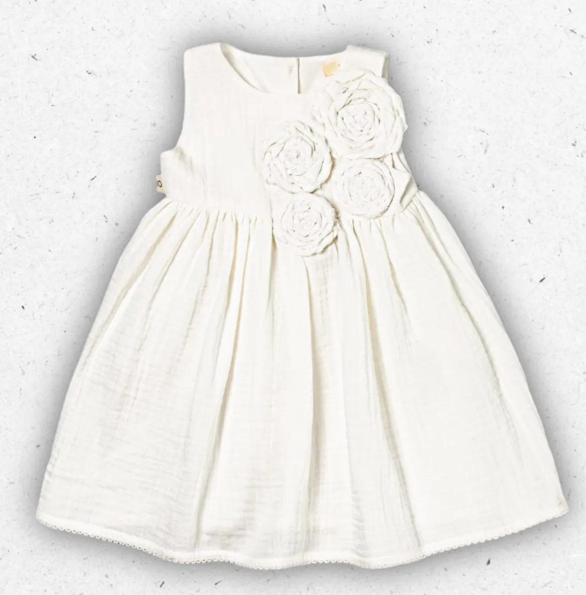 Abito smanicato da bambina Maperò in morbida garza di cotone color panna, con rose in tessuto applicate sul petto e gonna ampia arricciata.