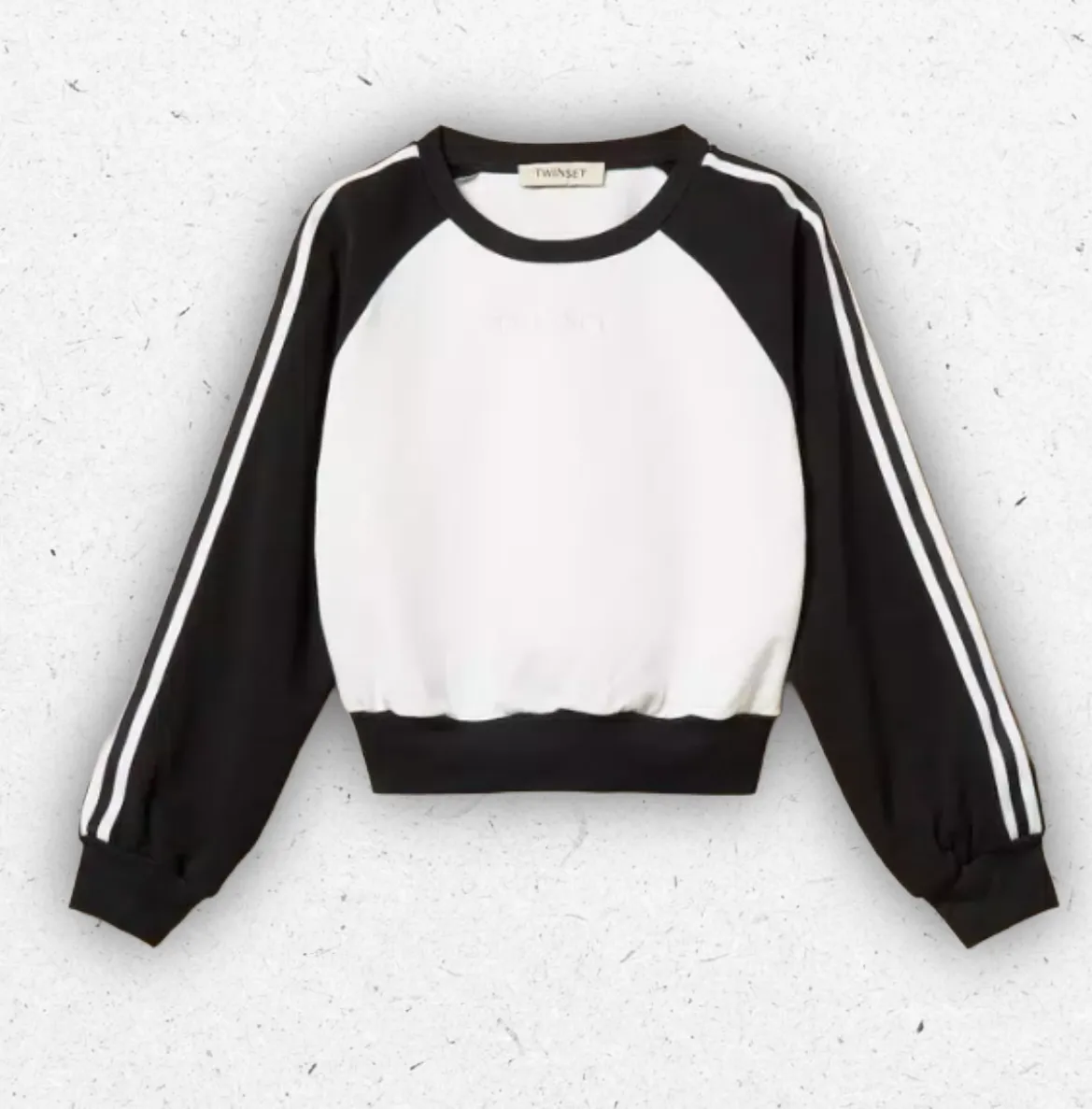 Felpa sportiva da bambina Twinset modello color block con corpo centrale bianco panna, maniche raglan nere e bande laterali a righe.