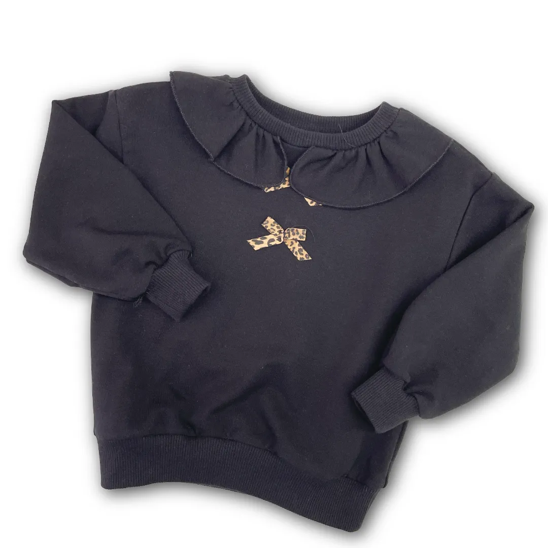 Felpa Please girocollo nera per bambina, con colletto arricciato e fiocco maculato applicato.