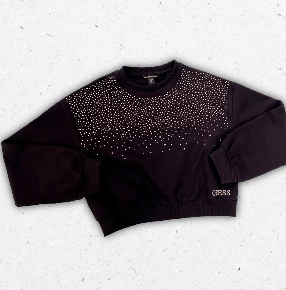 Felpa nera Guess da ragazza in cotone a girocollo con logo o dettagli in strass scintillanti e taglio corto alla moda.