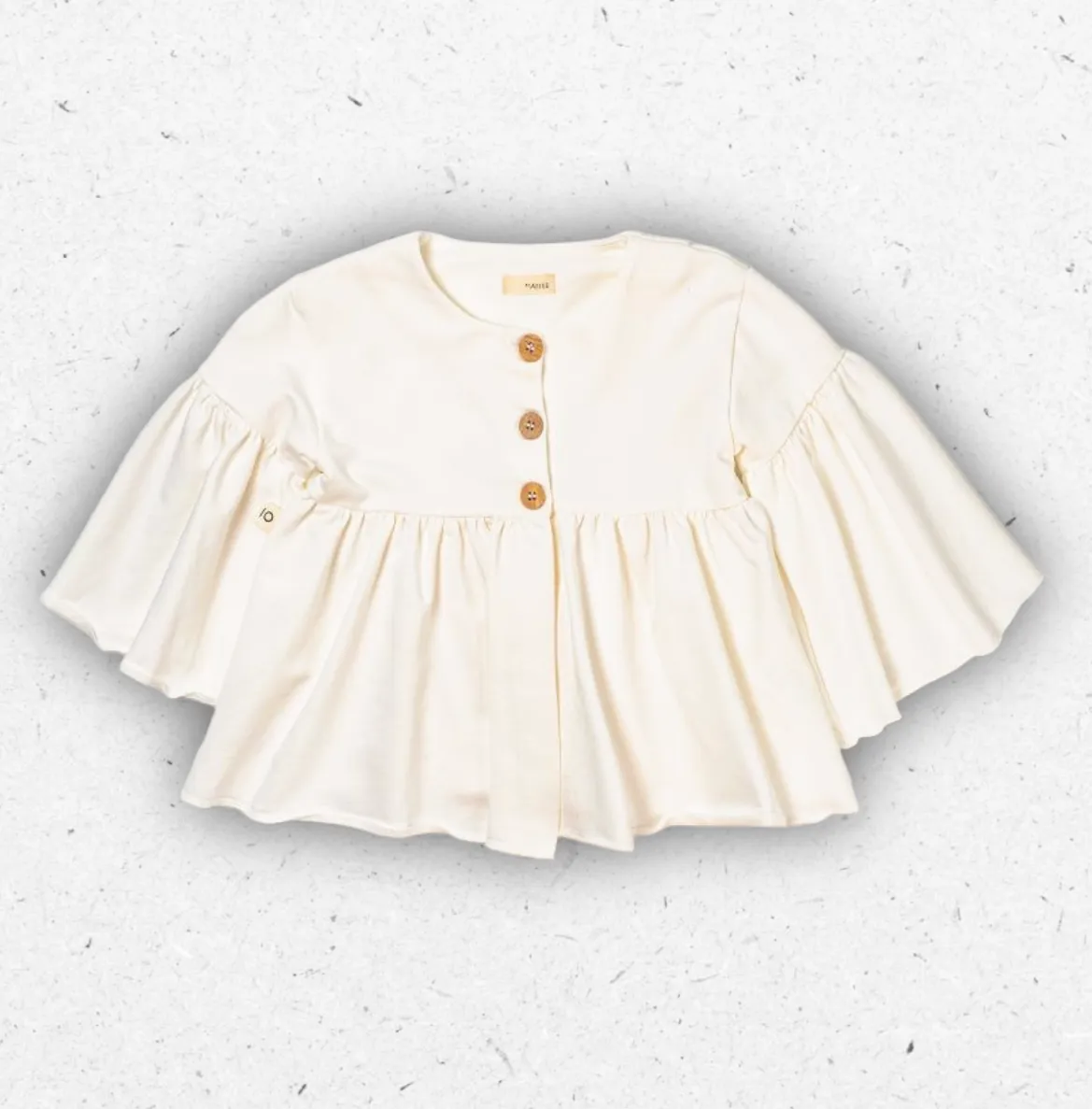 Giacca da bambina Maperò in felpa color panna, modello svasato con maxi maniche a volant e chiusura frontale con tre bottoni marroni.