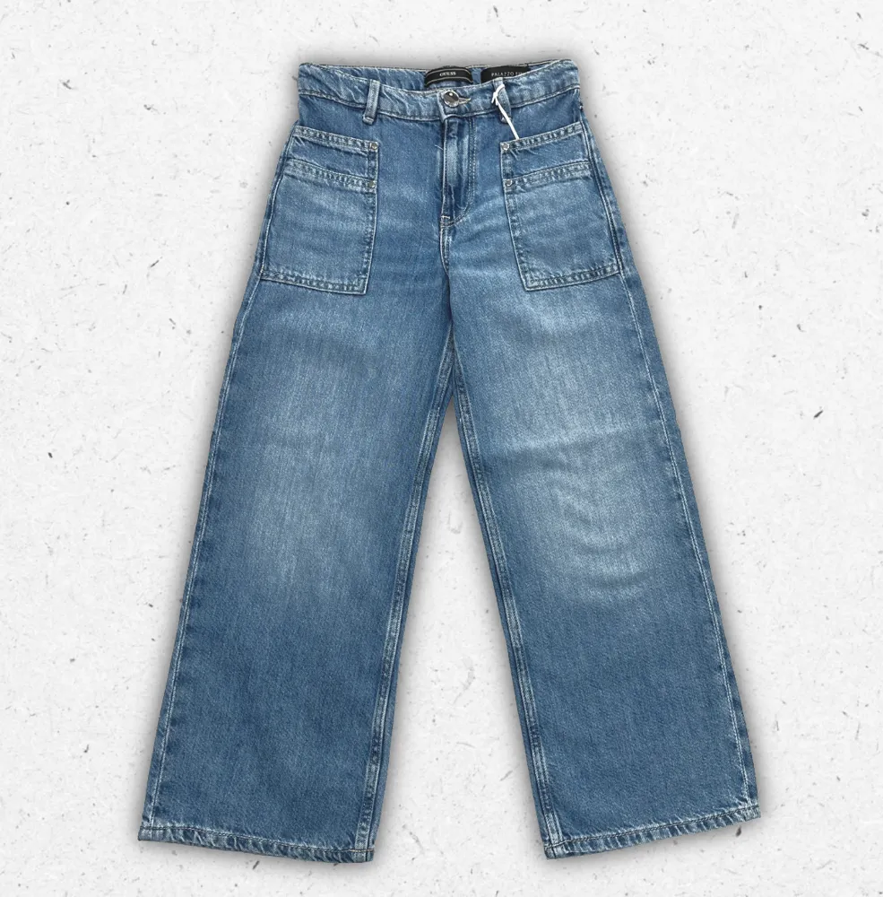 Jeans Guess da ragazza in denim elasticizzato blu con cinque tasche e logo iconico a triangolo applicato sul retro.