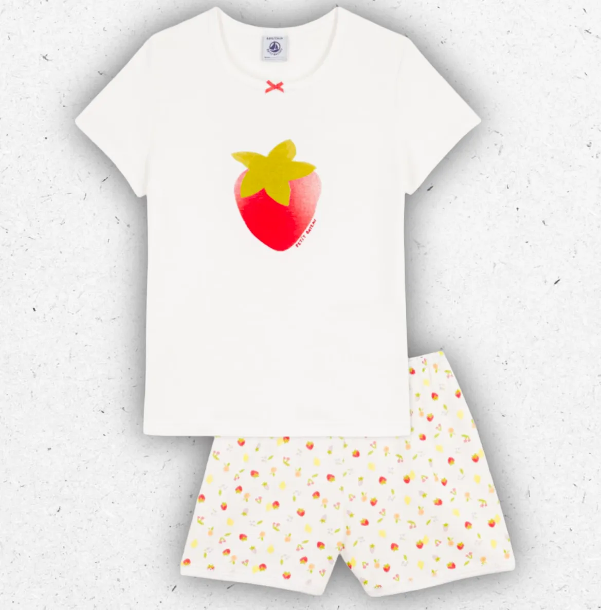 Pigiama corto da bambina Petit Bateau in cotone a costine bianco con stampa di frutti colorati e rifiniture picot.