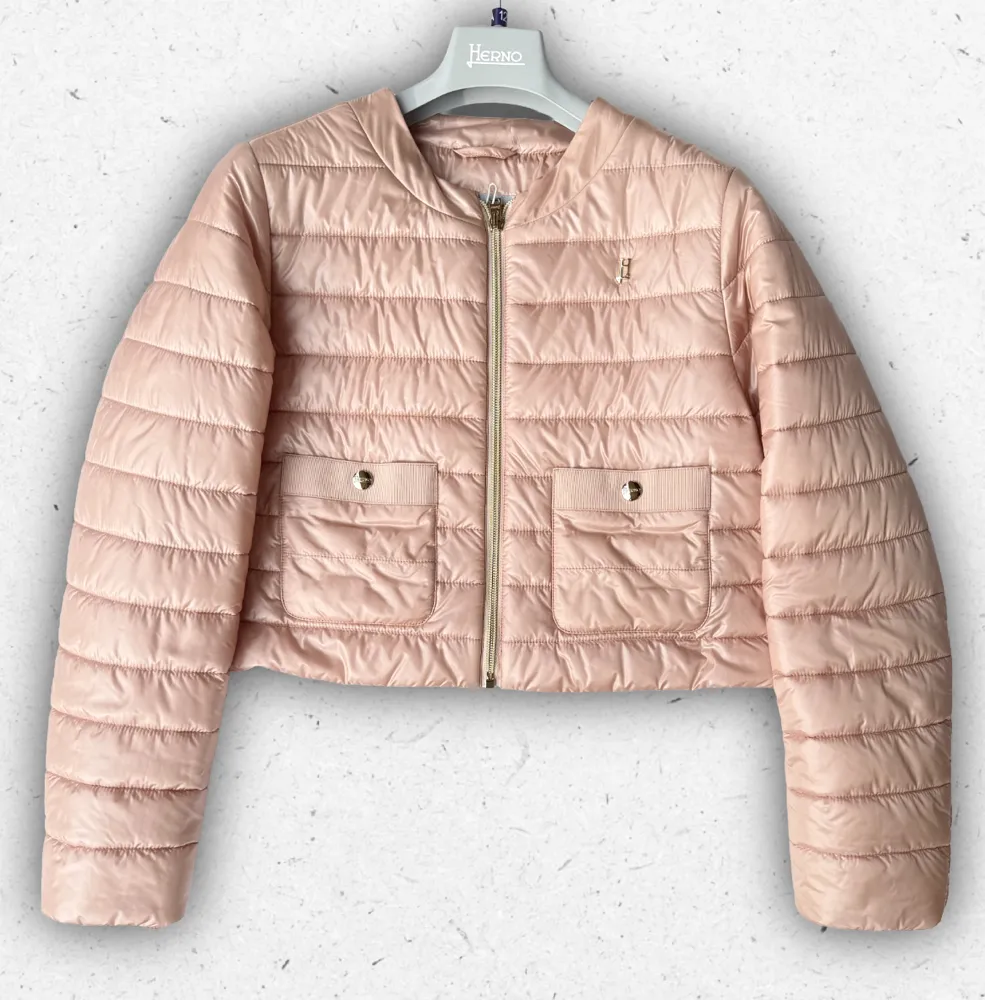 Piumino ultraleggero da ragazza Herno modello GI00090 con manica a tre quarti e collo alto, disponibile nei colori chantilly e rosa chiaro.