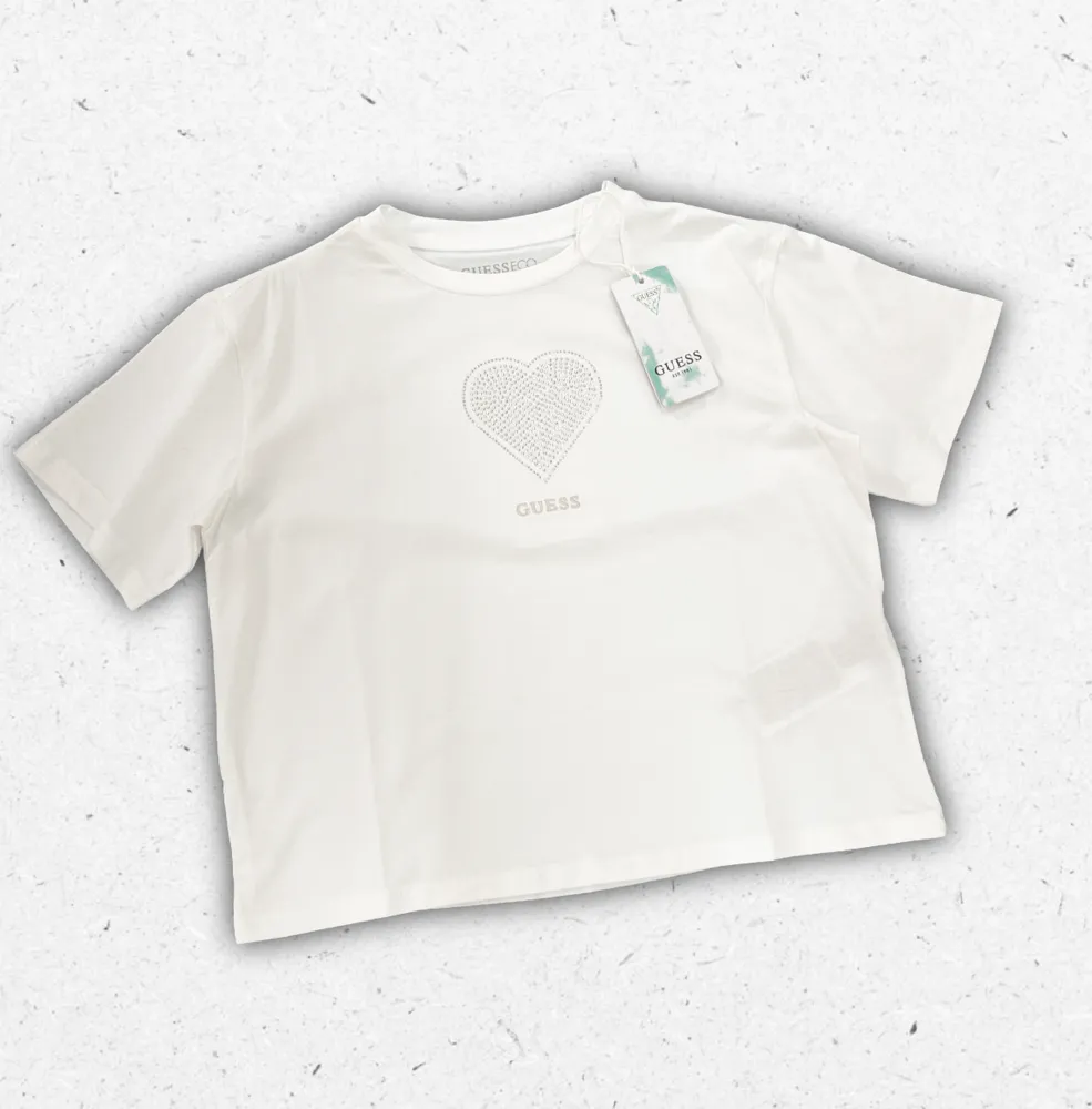 T-shirt bianca Guess da ragazza in puro cotone con logo iconico stampato centralmente sul petto.