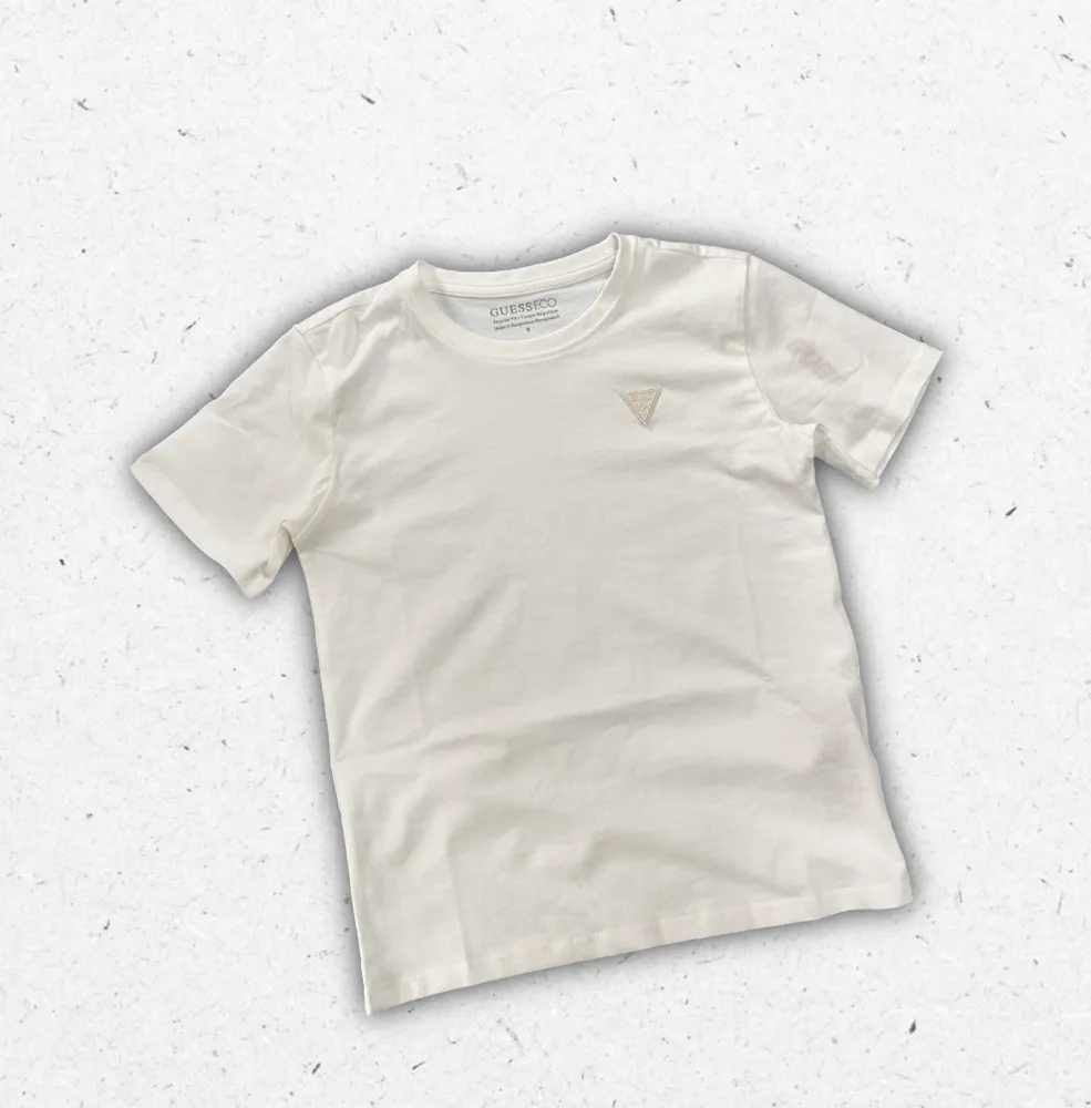 T-shirt bianca Guess da ragazzo in puro cotone con logo iconico stampato centralmente sul petto.