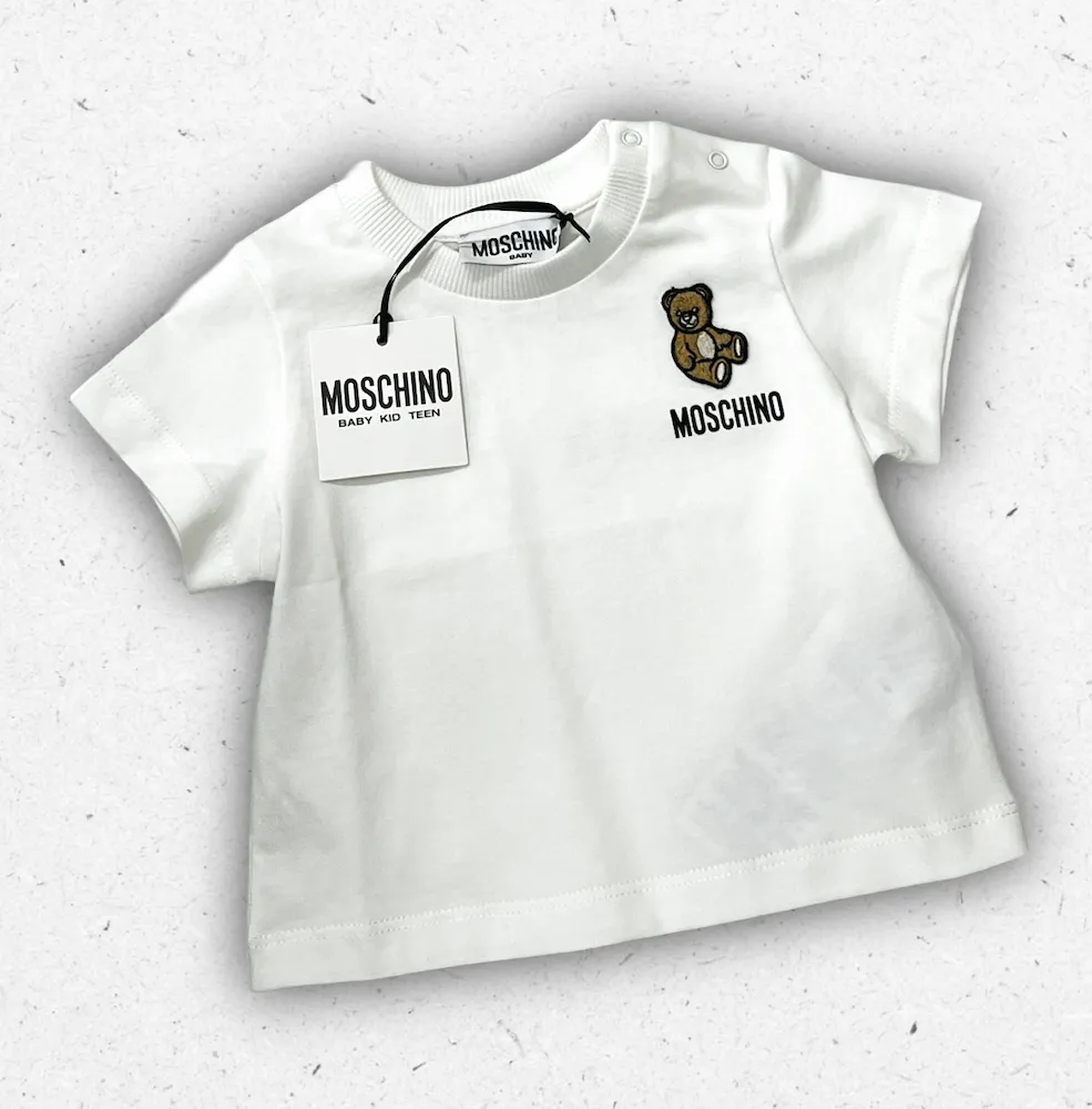 T-shirt bianca da neonato Moschino Baby modello MUM04T con logo Teddy Bear sul petto e bottoni automatici sulla spalla.