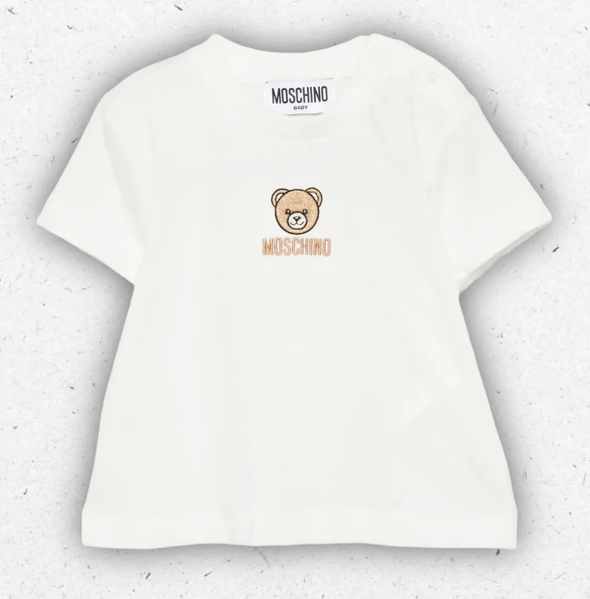 T-shirt da neonato bianca a maniche corte Moschino Kids in cotone con stampa frontale del logo nero, presentata con la sua scatola regalo ufficiale.