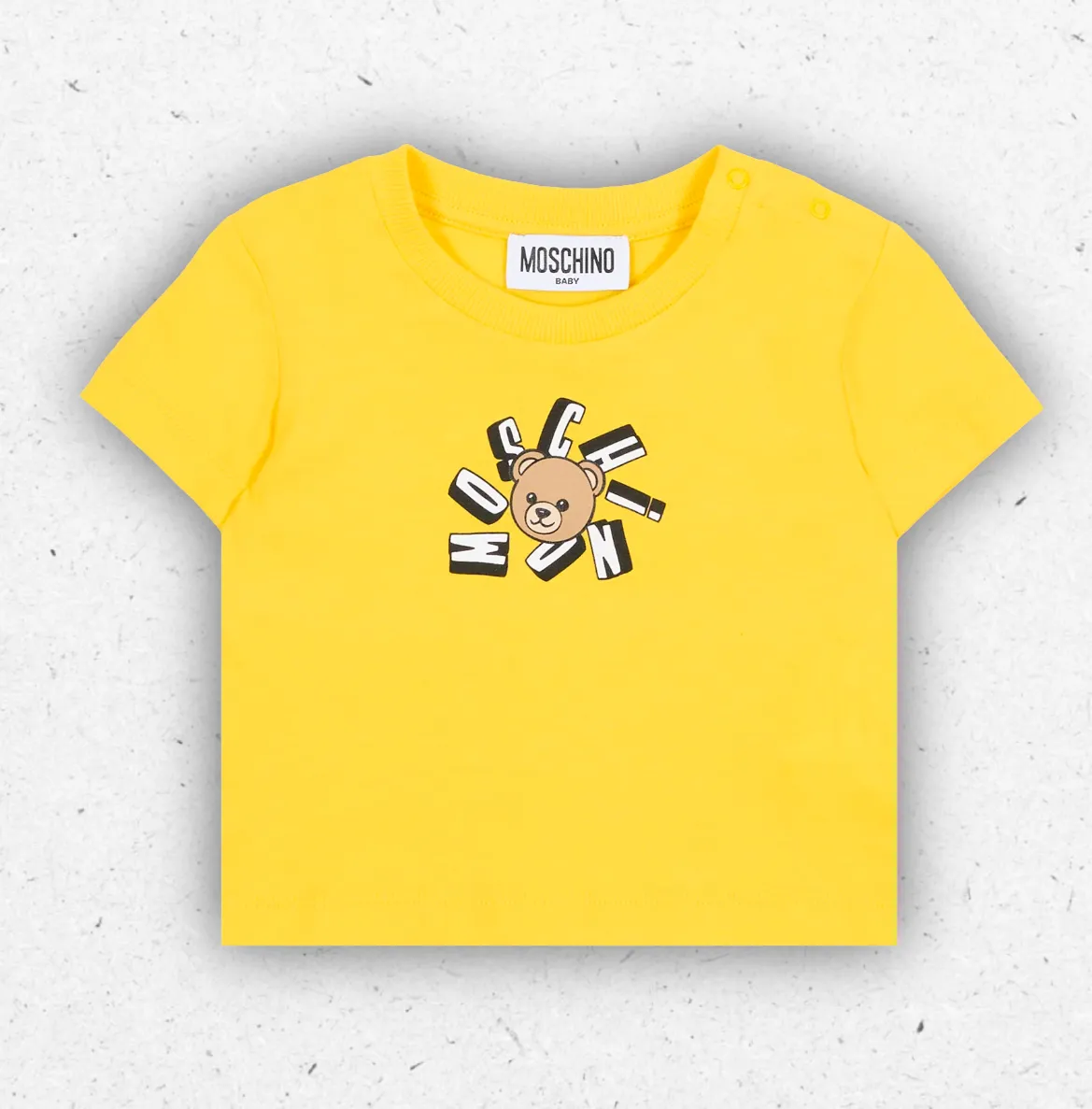 T-shirt estiva gialla per neonato firmata Moschino Kids in cotone con stampa frontale dell'orsetto Teddy Bear e logo nero, dotata di bottoni automatici sulla spalla.