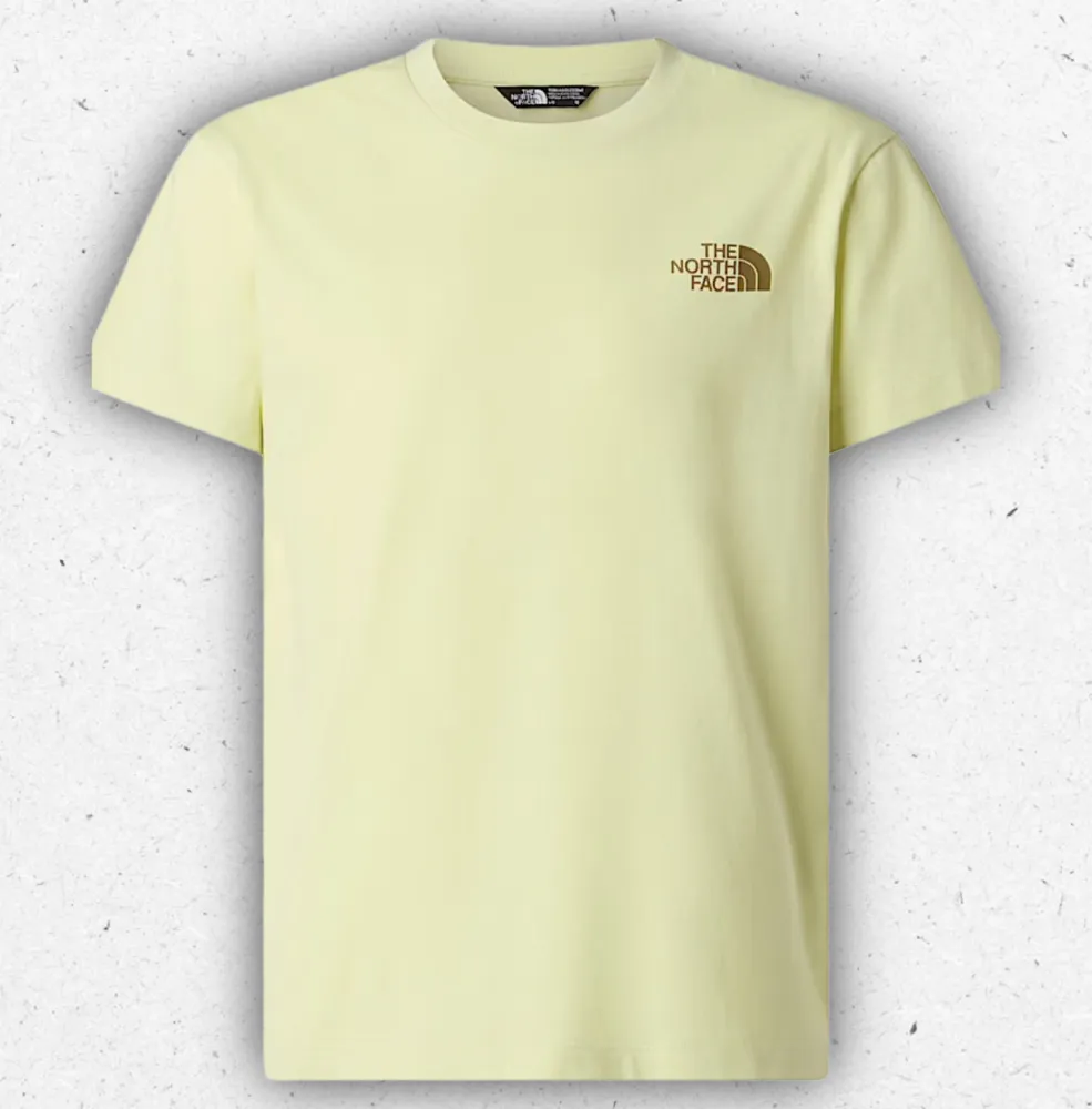 T-shirt da ragazzo The North Face Voyage Relaxed di colore giallo pallido con piccolo logo frontale e grande grafica colorata sulla schiena con scritte e icone outdoor.