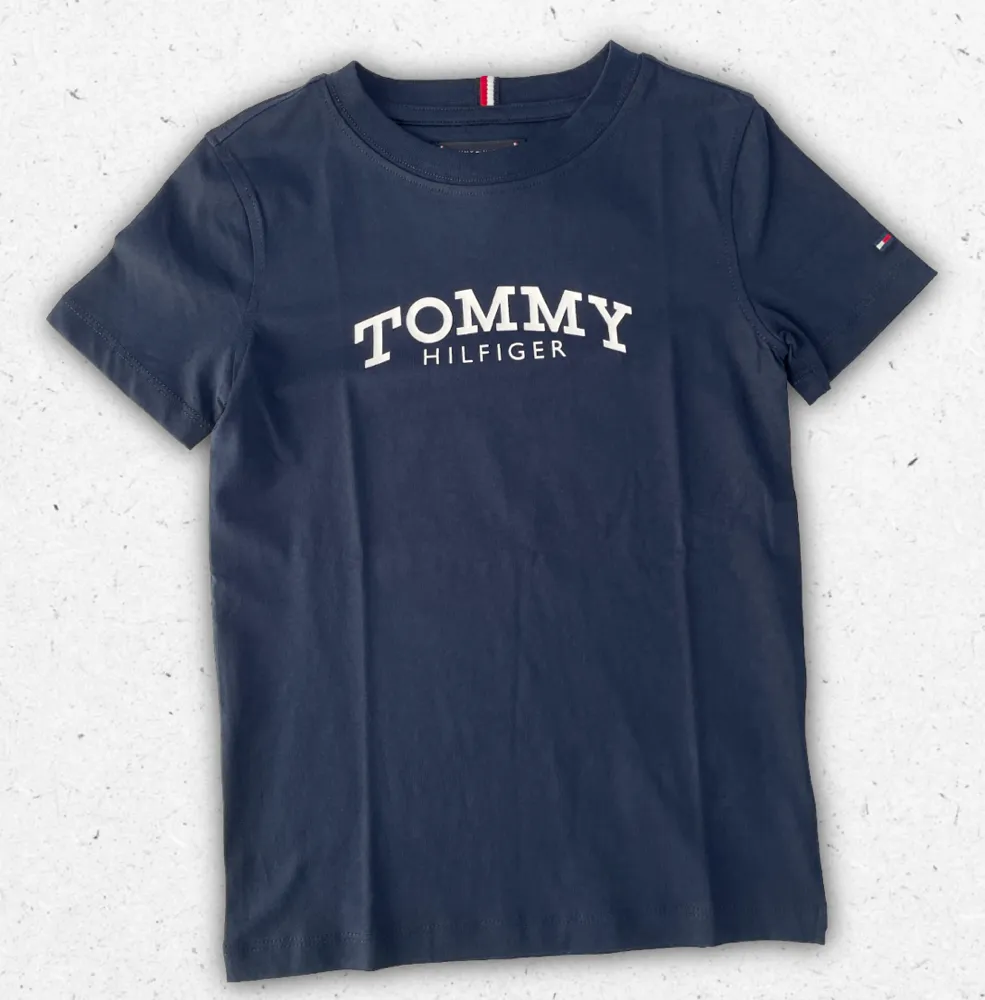 T-shirt Tommy Hilfiger da ragazzo con girocollo e logo flag ricamato, disponibile nei colori bianco e blu navy scuro.